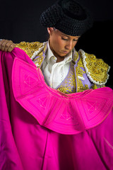 Naklejka premium Woman bullfighter holding capote pink on black background