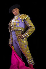 Woman bullfighter holding capote pink on black background