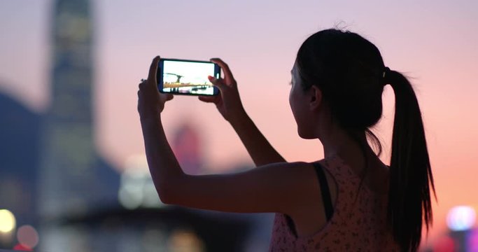 Woman take photo on cellphone in Hong Kong at night