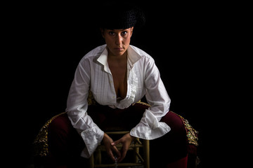 Woman bullfighter sitting on a wooden chair holding a rosary