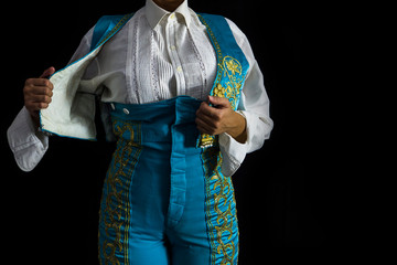 Woman bullfighter by dressing with vest on your back on a black background