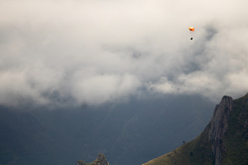 man with paraglider flying among the mountains