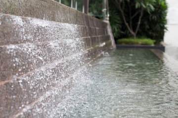 Waterfall in the fountain in garden, tree on background. Close-up, copy space