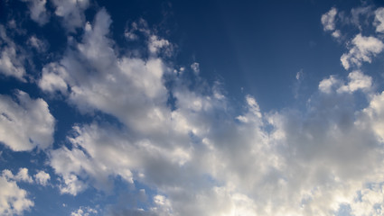 Beautiful puffy clouds with sun beams against blue skies.  