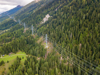 Aerial view of power line and pylon in alpine valley of Goms in Switzerland. Power grid through alps. 