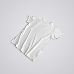 Unfolded  blank T-shirt  with shadows  lying on the studio background.