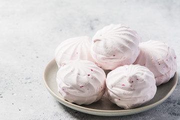 Pink marshmallows with blackcurrants on a plate. Light grey background