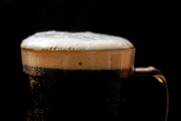 glass of beer on a black background, beer with foam.