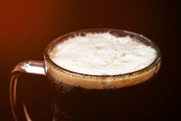 glass of beer on a black background, beer with foam.