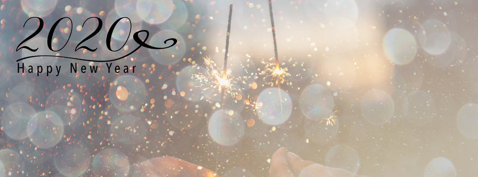 New Year banner, header for social media. Scales down to fit a facebook header size. Sparklers against a background with bokeh and falling snow effect. Happy New Year 2020 quote.