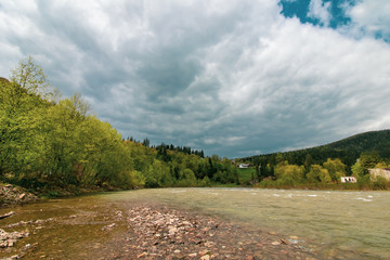 River in the mountains. Beautiful landscape of Carpathians in Ukraine. Yaremche. Thundercloud, storm clouds. Travel background. Pine forest, pinewood.