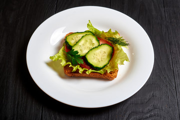 Sandwich with fresh vegetables, vegetarian. Salad, cucumbers, tomato on toasted toast.