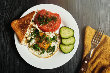 Grilled egg and grilled tomato on a plate on a wooden background. Fast and easy to prepare breakfast.