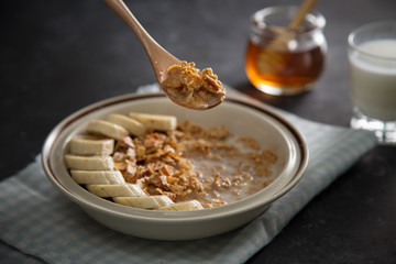 Plate with integral oatmeal flake with banana fruits, human hand with spoon