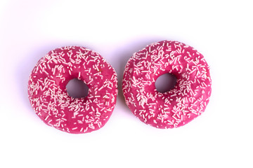 Two pink glazed donuts laying next to each  other on white background