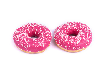 Two little pink donuts decorated with white sprinkles on white background