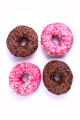 Two chocolate and two pink glazed tasty donuts laying isolated from each other