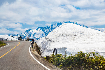 Winding roads with snow, mountains and the blue sky as the background in Japan
