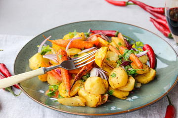 warm salad of baked potatoes and carrots with red onions, spices and tomatoes