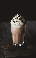 Chocolate cookie milkshake with whipped cream on wooden table
