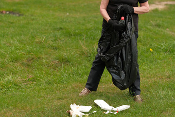 man picking up plastic household waste in park