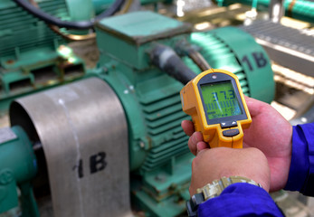 Workers are measuring the temperature of motor with infrared thermometer