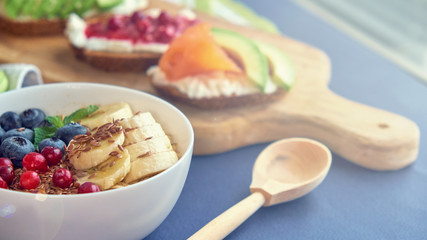 breakfast top view black background. oatmeal with berries, toasts on a wooden tray, nuts, coffee