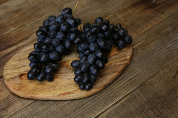 bunch of organic juicy blue-black grapes on a wooden rustic table with copy space for text.