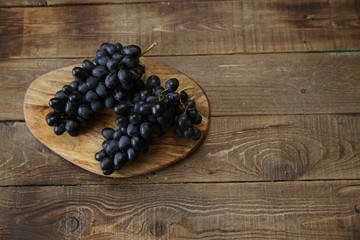 Close-up bunch of organic juicy blue-black grapes on a wooden rustic table with copy space for text. Flat lay. Top view.