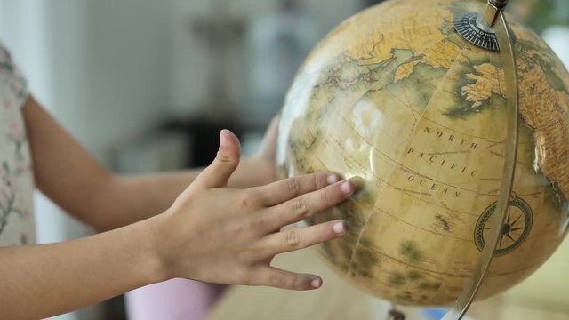 Girl spinning terrestrial globe. Travel dream concept