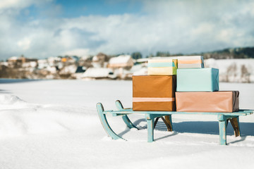 Vintage Schlitten mit Geschenken im Schnee, Dorf im Hintergrund