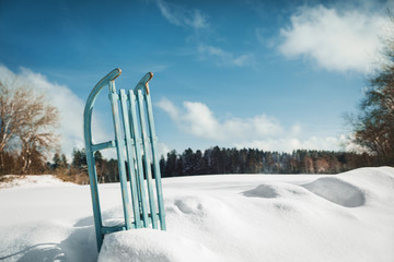 Shabby Schlitten aus Holz steckt im Schnee, Landschaft im Hintergrund