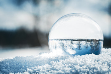 Fotokugel oder Glaskugel im Schnee, Winterlandschaft spiegelt sich darin, Konzept Winter