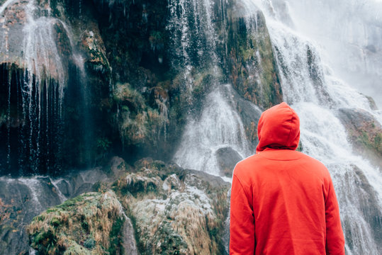 un homme visitant une chute d'eau gel&eacute;e dans le jura