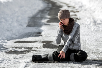 Frau nach einem Sturz auf Glatteis und Schnee, Notruf durch Smartphone aufgrund einer Verletzung
