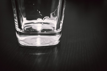 Square Bottom of Empty Beer Glass on Dark Table Surface. Bubbles Left from the Beer Head or Collar, Frothy Foam on Top of the Glass.