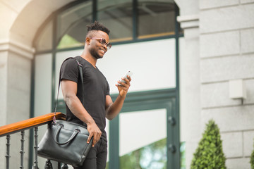 handsome young african man in a t-shirt with a phone in his hand