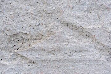 Concrete wall with small stones and bumps. Light gray color.