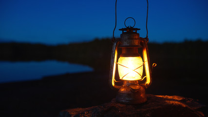 Gasoline lantern on a rock in the deep forest near lake at night. © raland