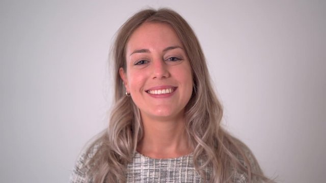 Close up footage portrait of beautiful blonde caucasian woman smiling and laughing at the camera isolated on neutral background. In facial expression and happiness concept.