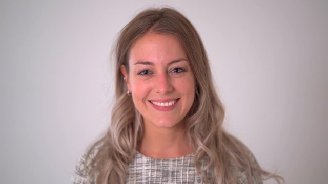 Close up footage portrait of beautiful blonde caucasian woman smiling and laughing at the camera isolated on neutral background. In facial expression and happiness concept.