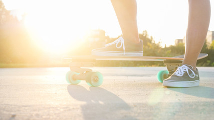 CLOSE UP Young girl with leg placed on skateboard relaxing at sunset