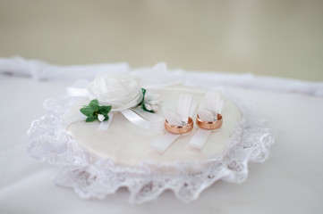 Fototapeta na wymiar Couple of gold wedding rings on the white pad