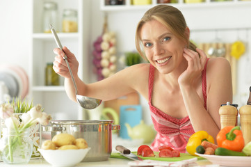 Portrait of a beautiful young woman cooking in kitchen