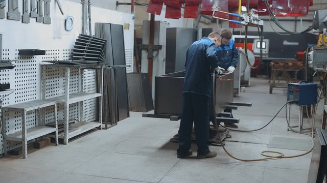 Workers welds metal sheets with spot welding. Factory production