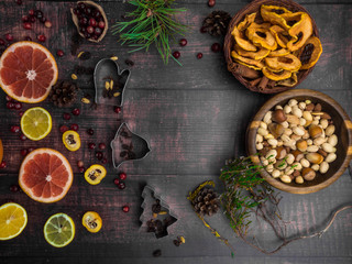 Food background with christmas spices, dried apples, nuts, citrus fruits, cydonia, cranberries, raisin, and baking dish on wooden background.Top view with copy space