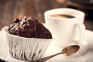 Chocolate muffins with banana in white paper cups on dark wooden background. Party food concept.