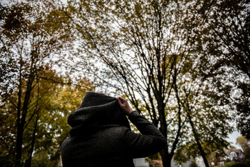 A woman pulls up her hoodie on a cold autumn day.