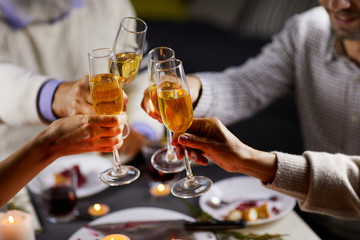 Portrait of people holding glasses with champagne and toasting with it during holiday dinner at the table
