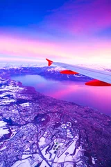 Fototapete Violett Erstaunliche Aussicht aus dem Flugzeugfenster während des Sonnenuntergangs über den Bergen in der Schweiz